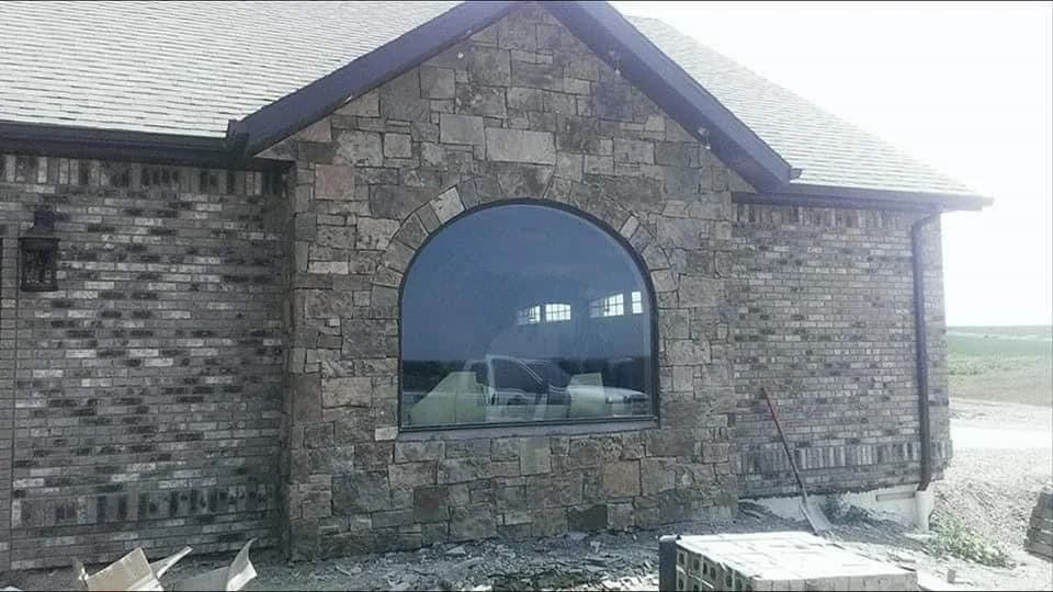 Stone exterior wall with a large arched window.