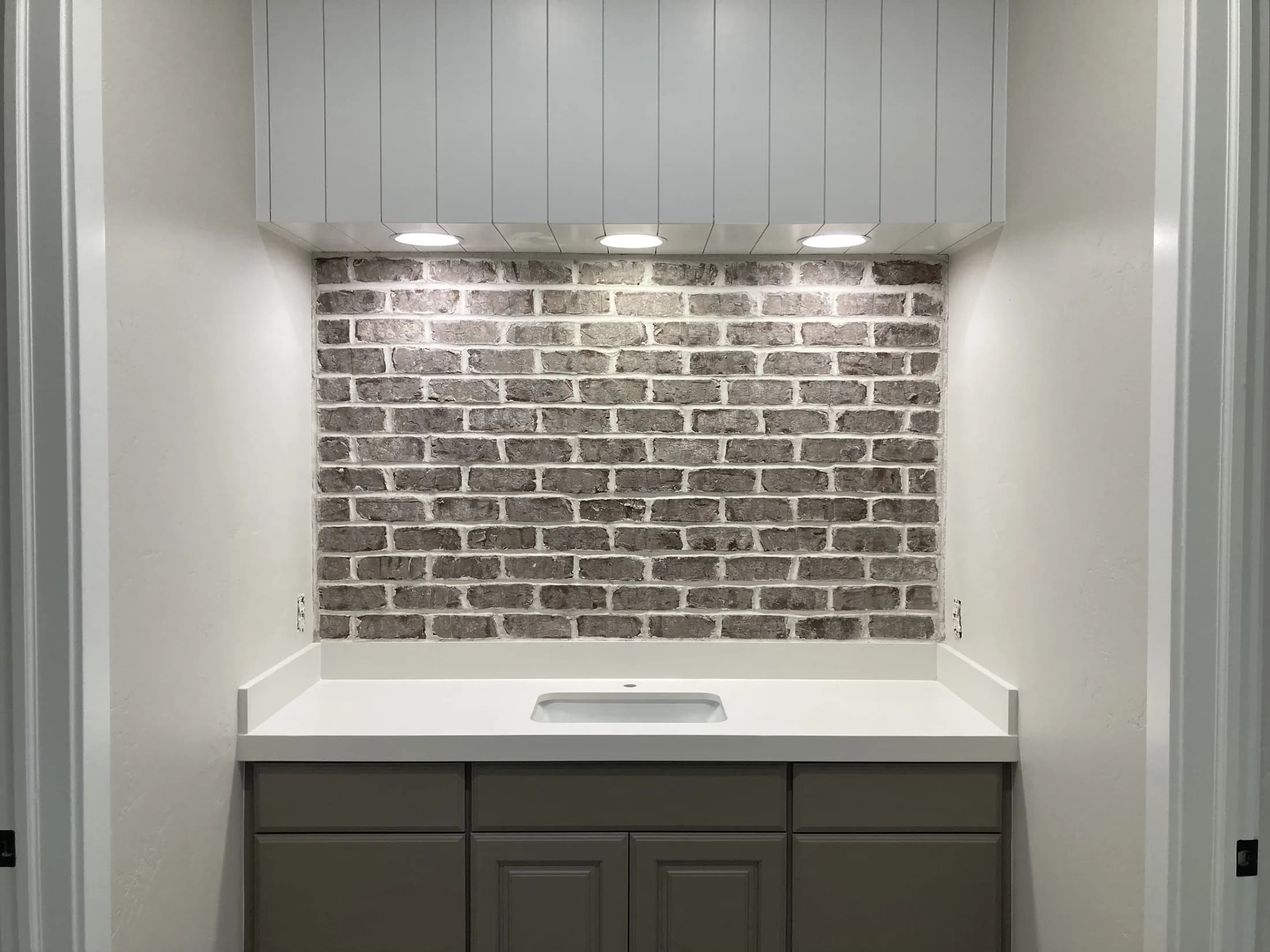 Gray-brick backsplash above a finished wet bar with custom cabinetry.