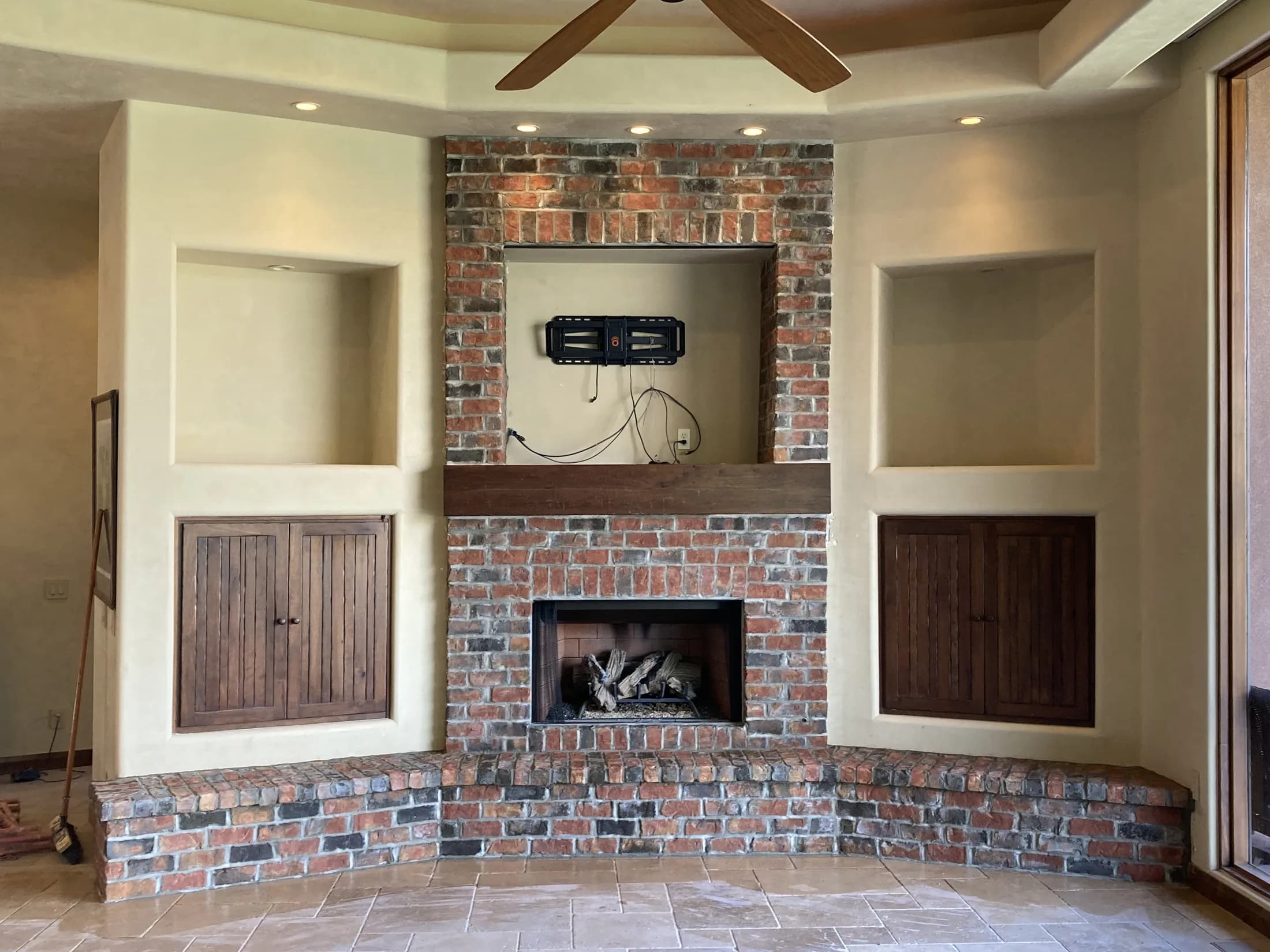 Reclaimed-brick fireplace with built-in wood cabinets and display niches.