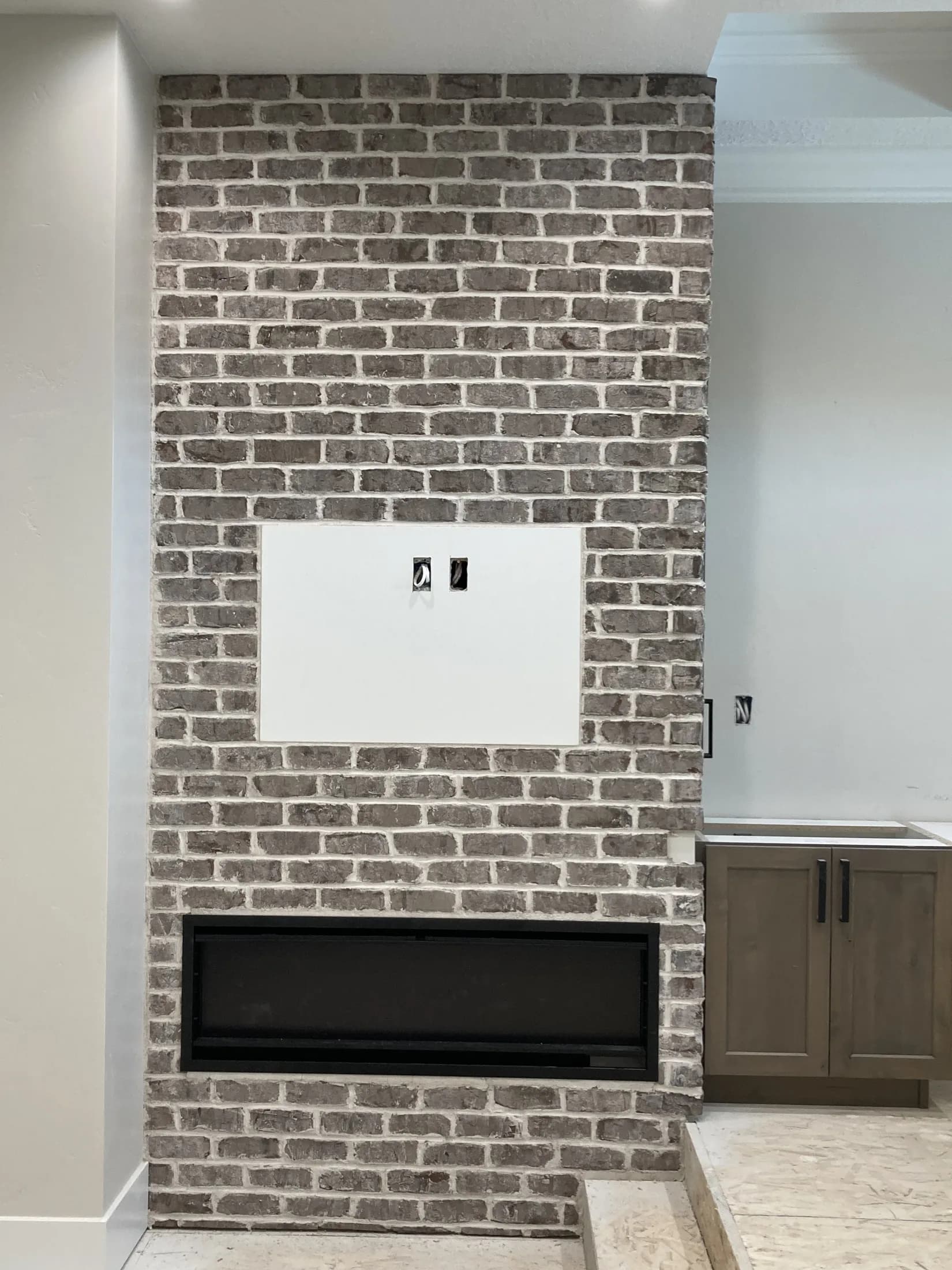 Gray-brick fireplace wall with low custom cabinetry.
