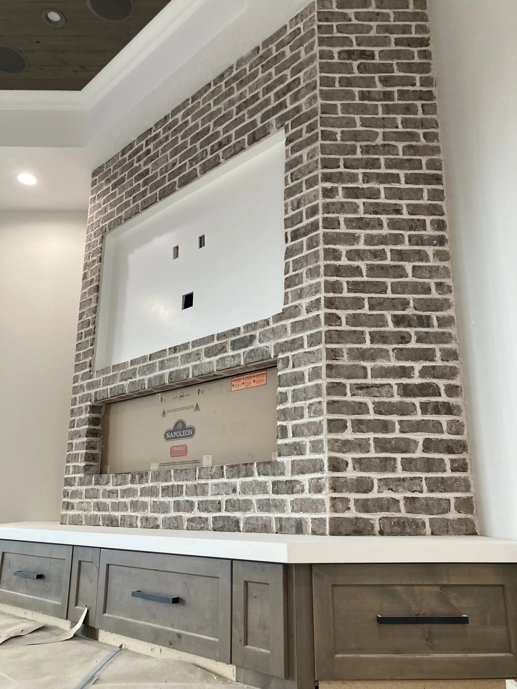 Gray-brick linear fireplace with integrated custom cabinetry.