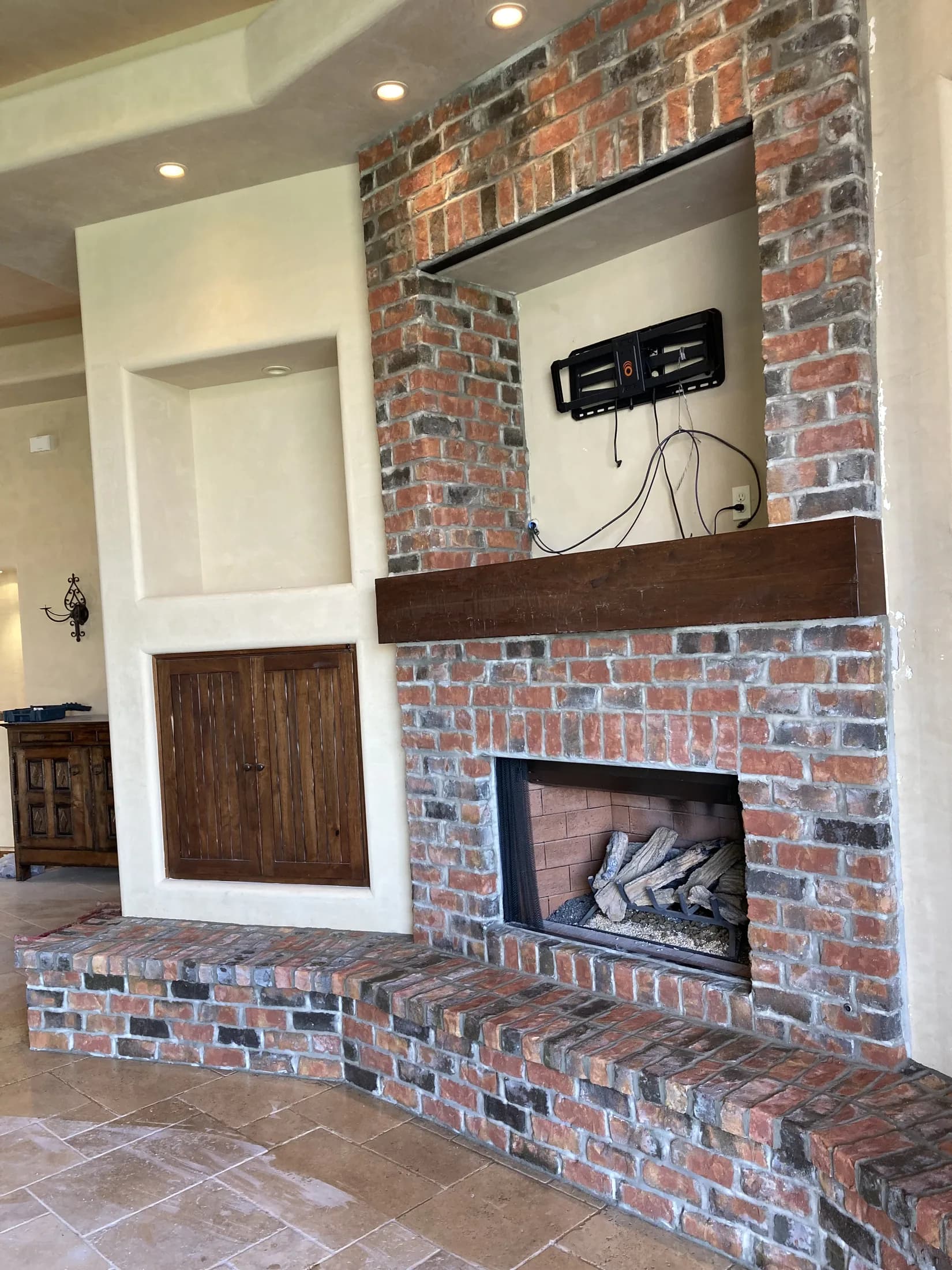 Reclaimed-brick fireplace and media wall with a raised hearth.
