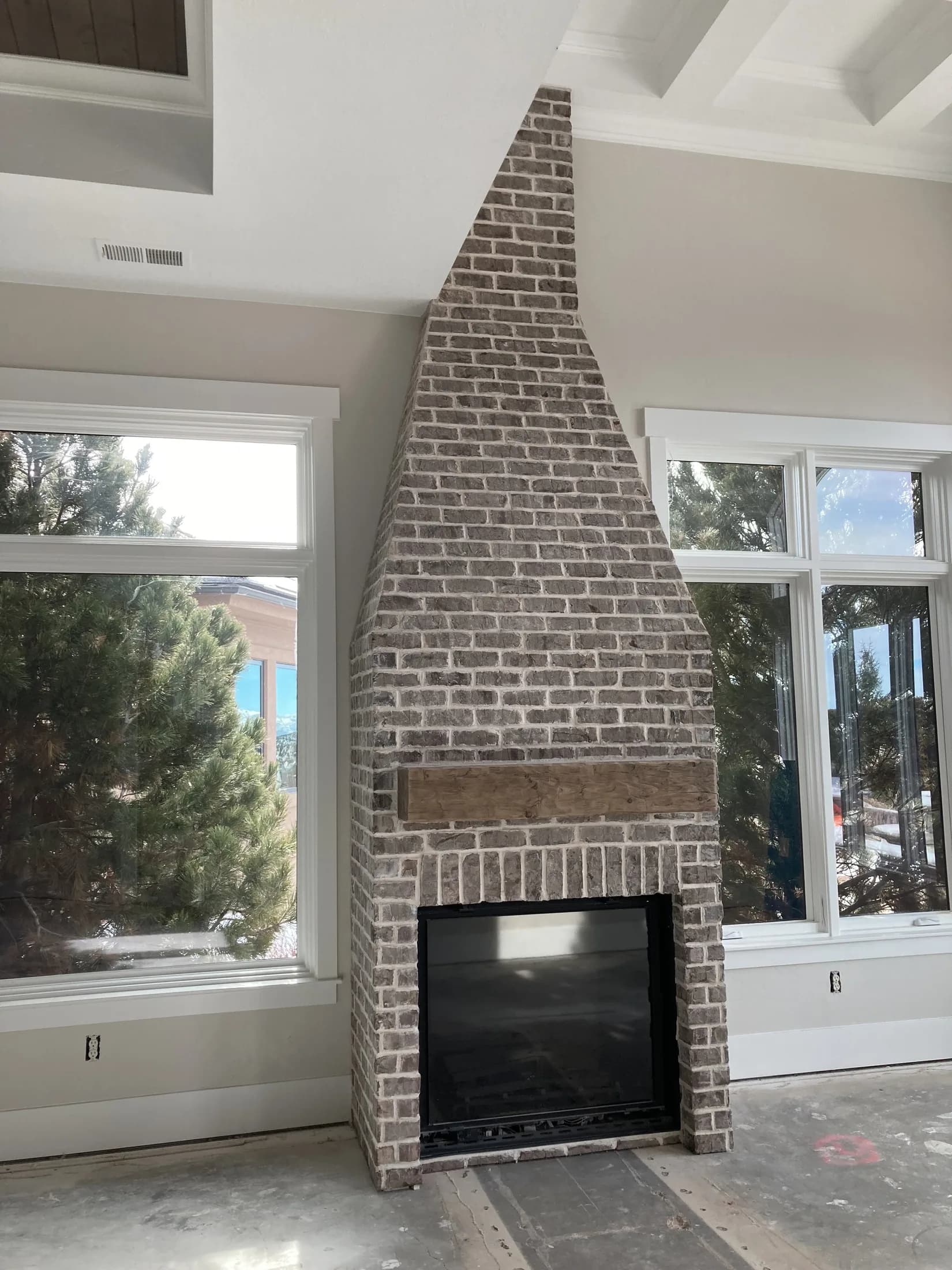 Tall gray-brick fireplace centered between floor-to-ceiling windows.