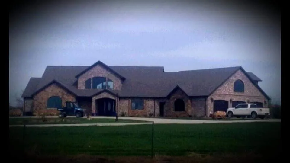 Large brick-and-stone residence viewed across the front lawn.