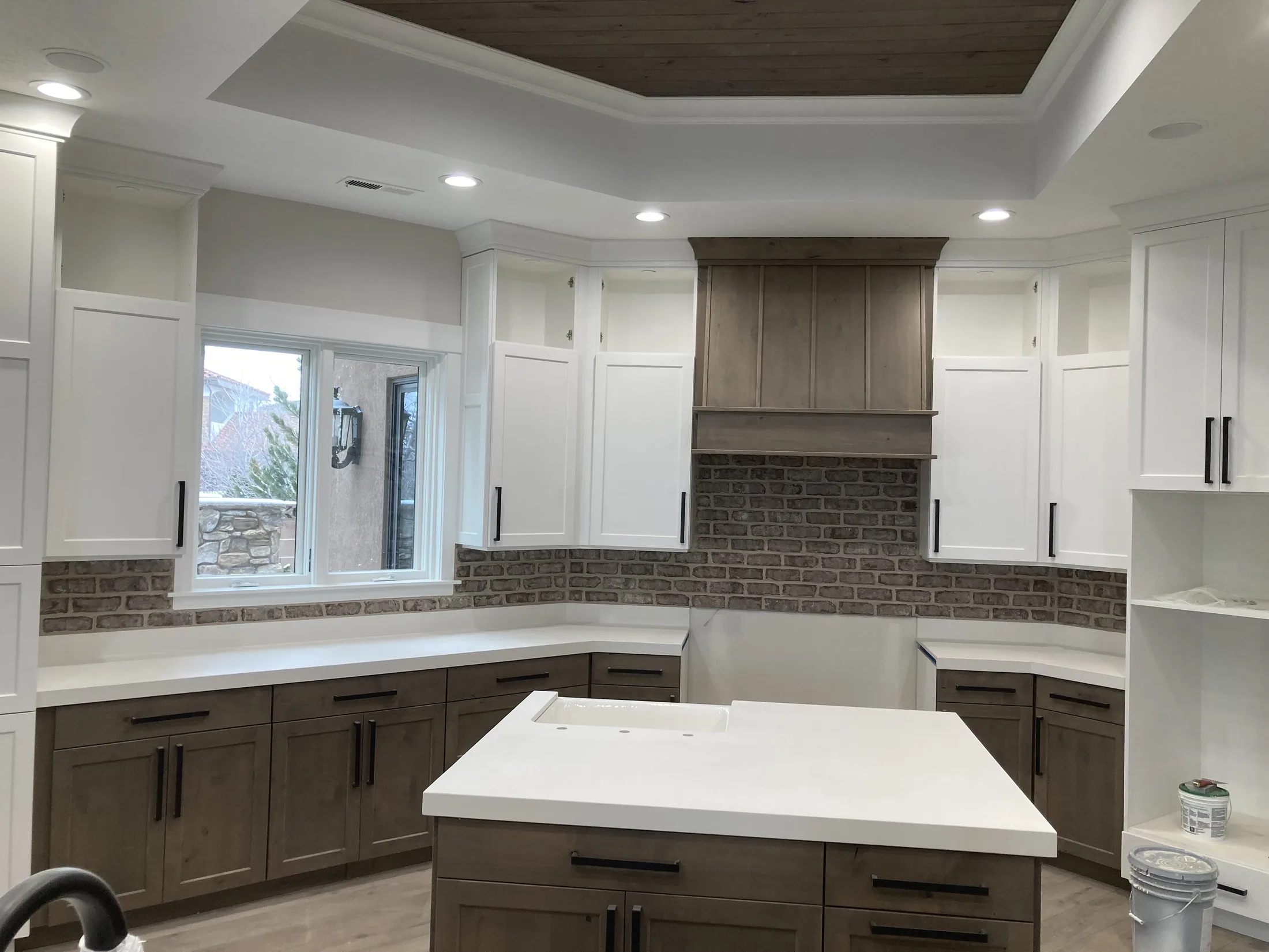 Finished kitchen with two-tone cabinetry, quartz island, and brick backsplash.