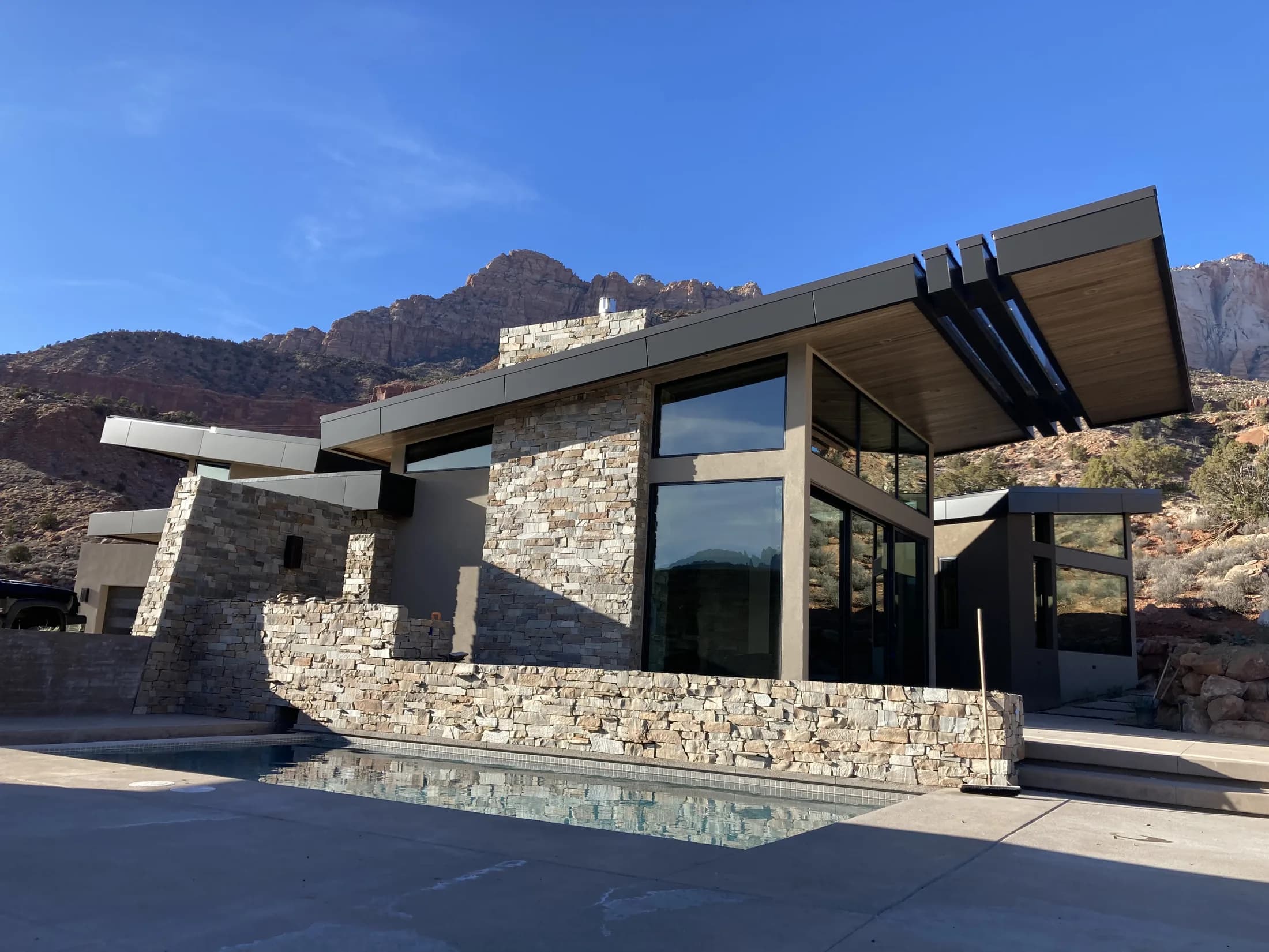 Modern stone-and-glass residence set against Southern Utah red-rock cliffs