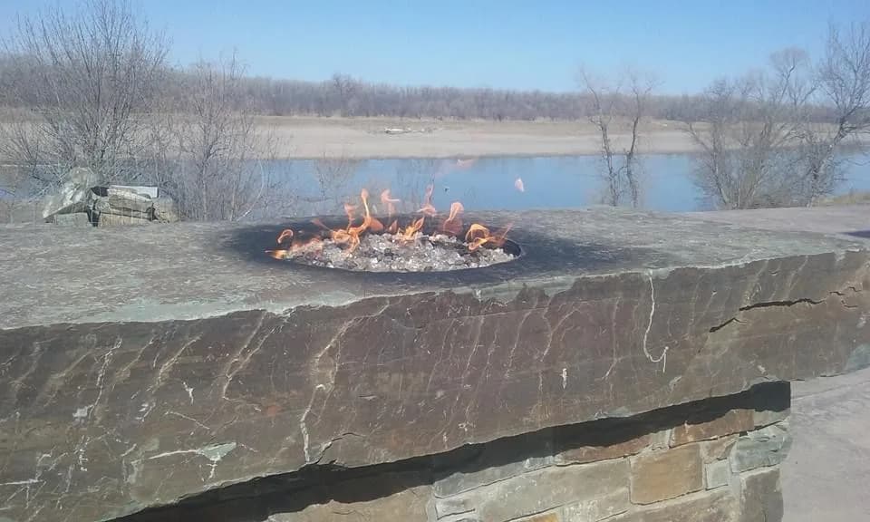 Stone firepit burning beside an open landscape.