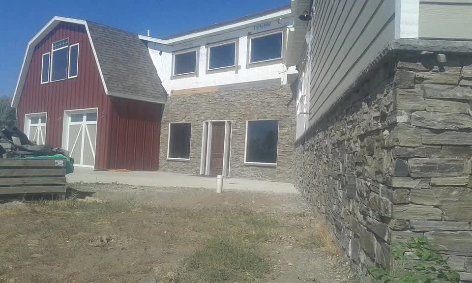 Residential stone addition beside a red outbuilding.