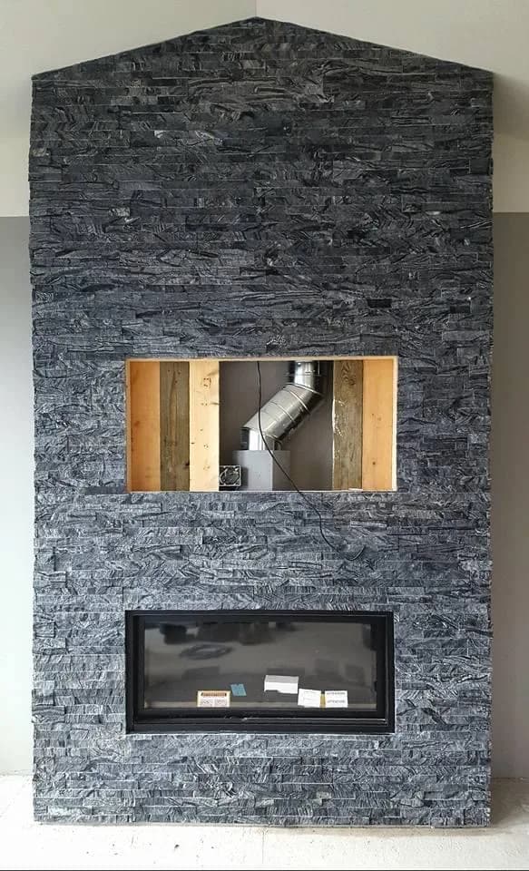 Stacked-stone fireplace surround during installation.