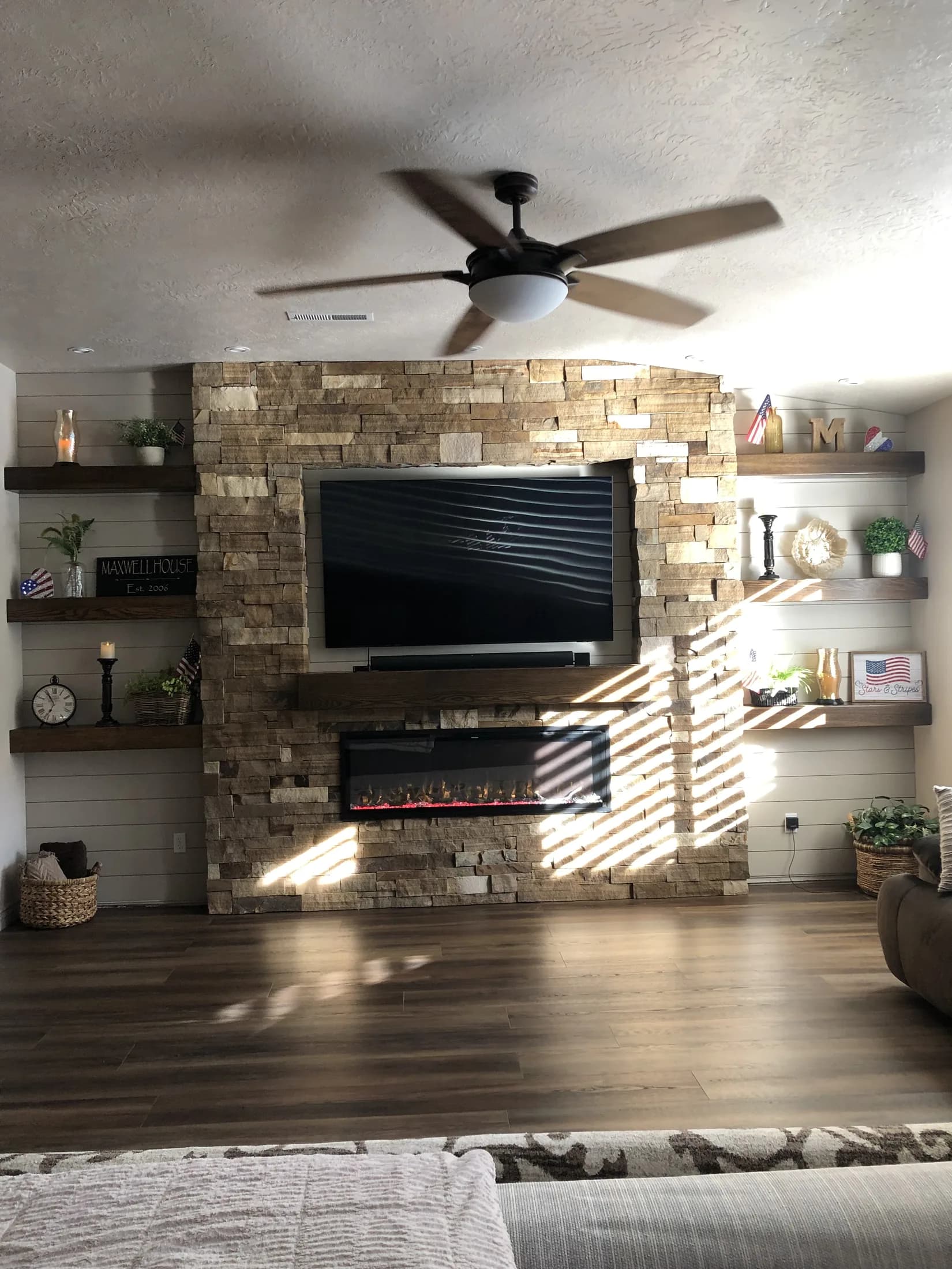Stacked-stone fireplace and television wall with floating wood shelves