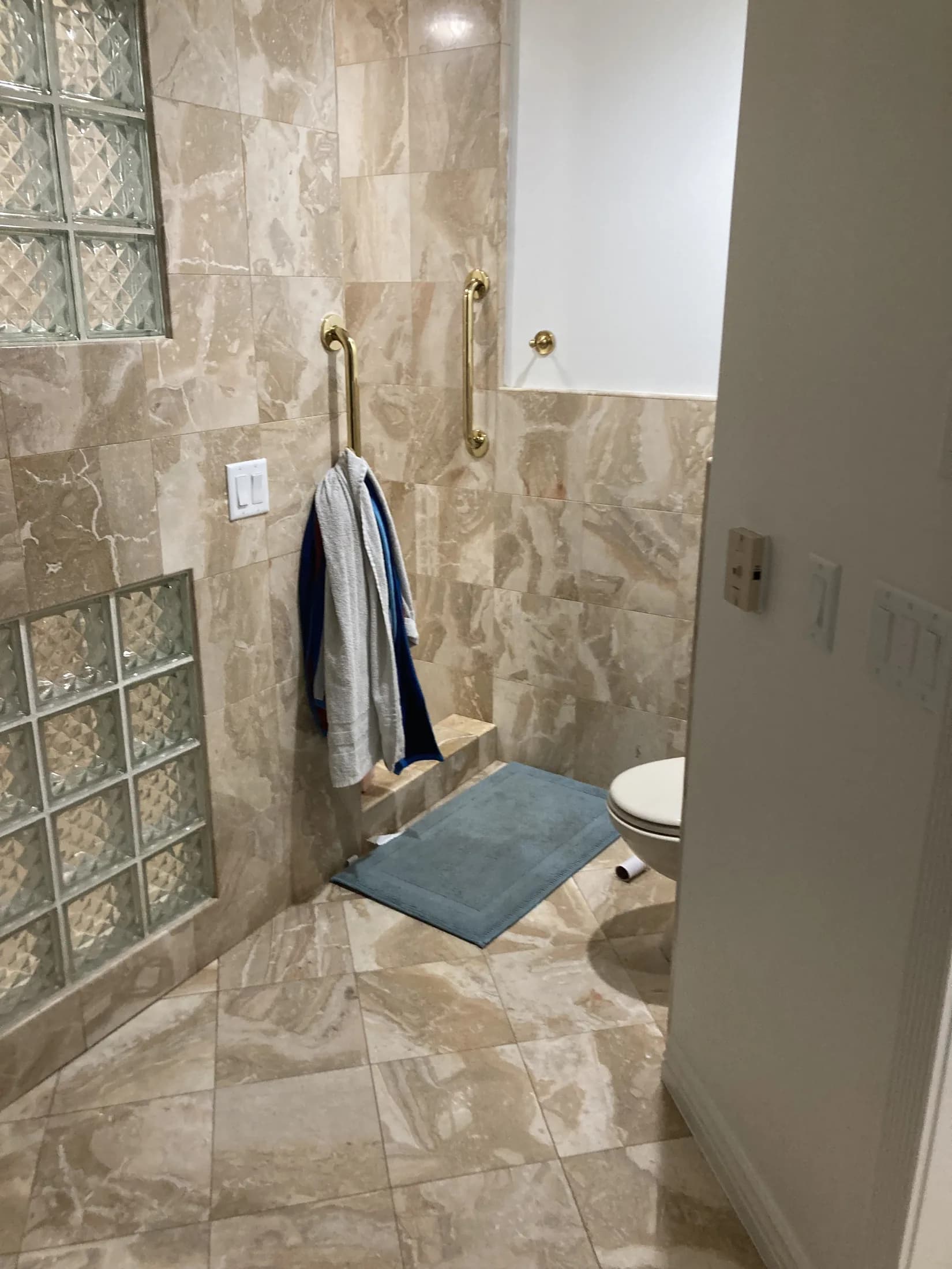 Stone-tile bathroom with a glass-block shower wall.